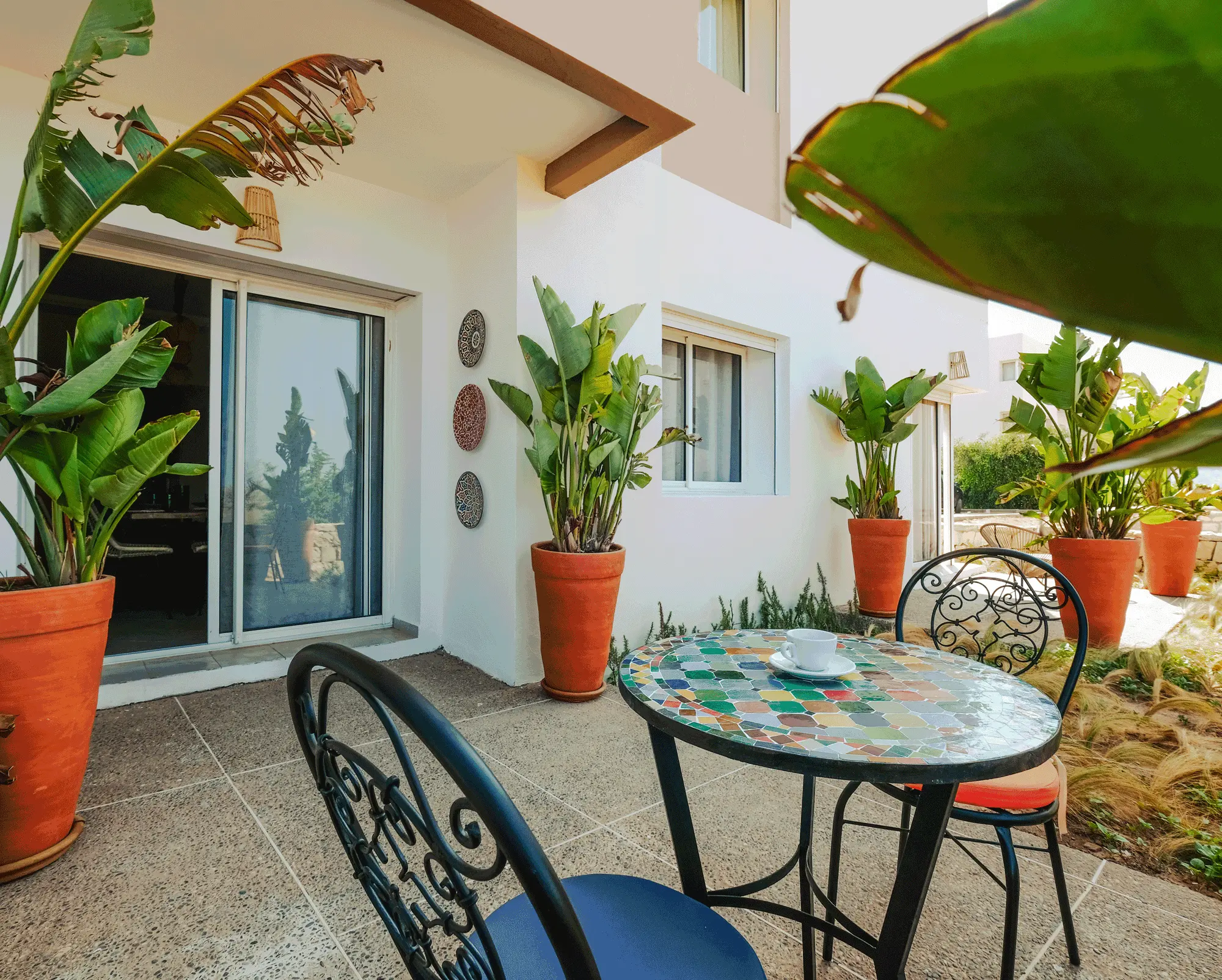 Terrasse extérieure avec table mosaïque et plantes vertes